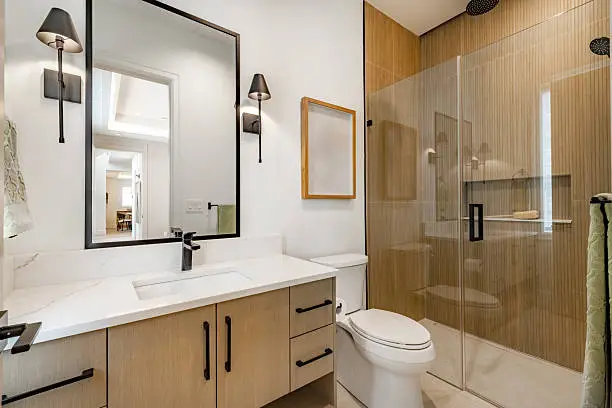 Skilled remodeler measuring shower wall and plumbing layout for precise bathroom renovation, Remodeler installing new vanity and mirror in an older Antioch bathroom