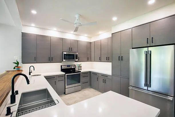 Homeowner reviewing budget-friendly kitchen material samples before renovation begins, Homeowner enjoying remodeled kitchen with new cabinets, counters, and brighter lighting